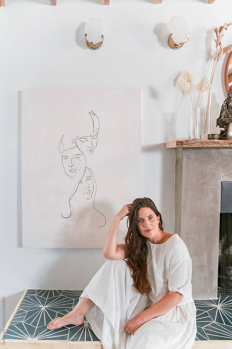 artist sits by her artwork hung on the wall