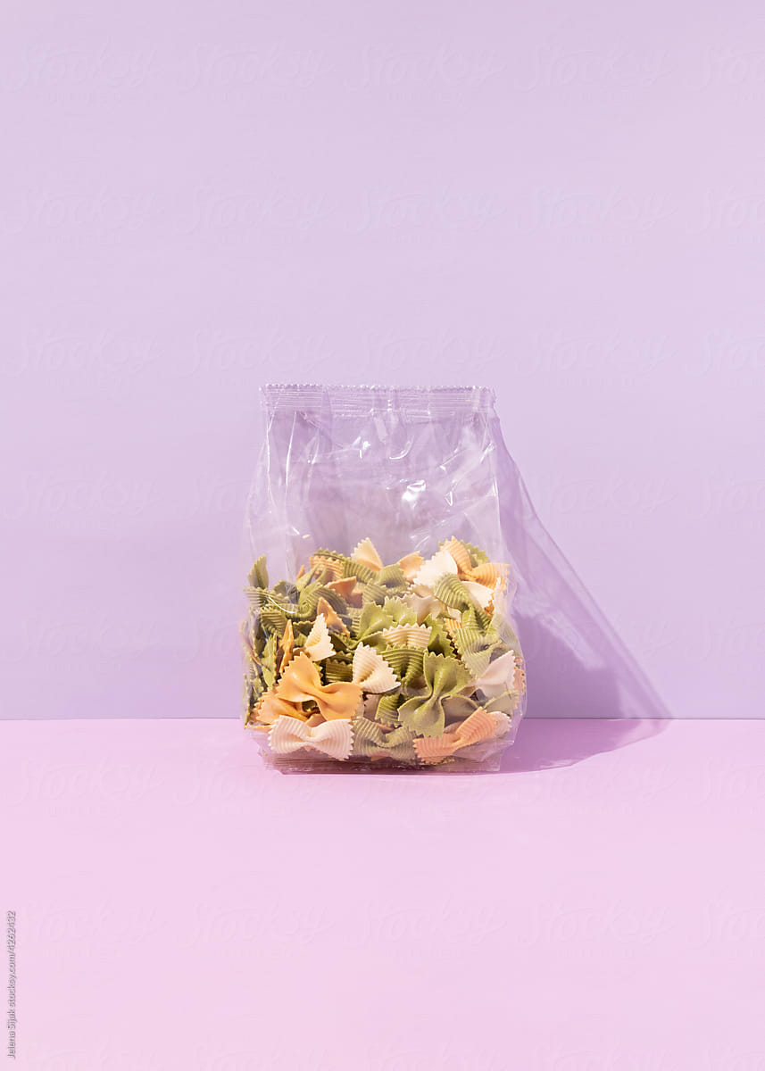 Bag of yellow, orange and a green macaroni pasta on pastel backgrounds