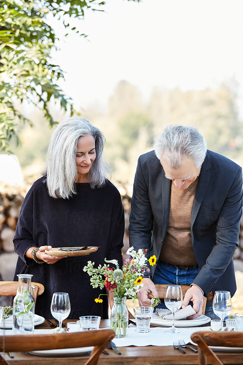 Senior couple setting the table for a Farm To Table dinner party at their home