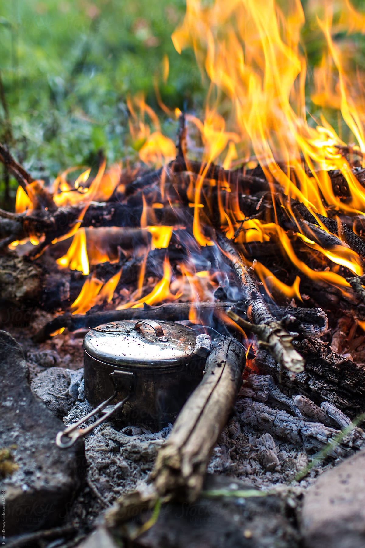 A meal cooks in a metal pot over a campfire