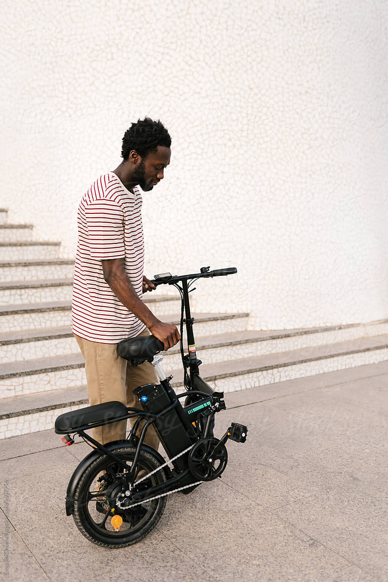Black man standing on street with electric bike