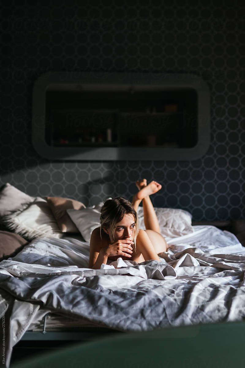 Naked woman on bed in bedroom.