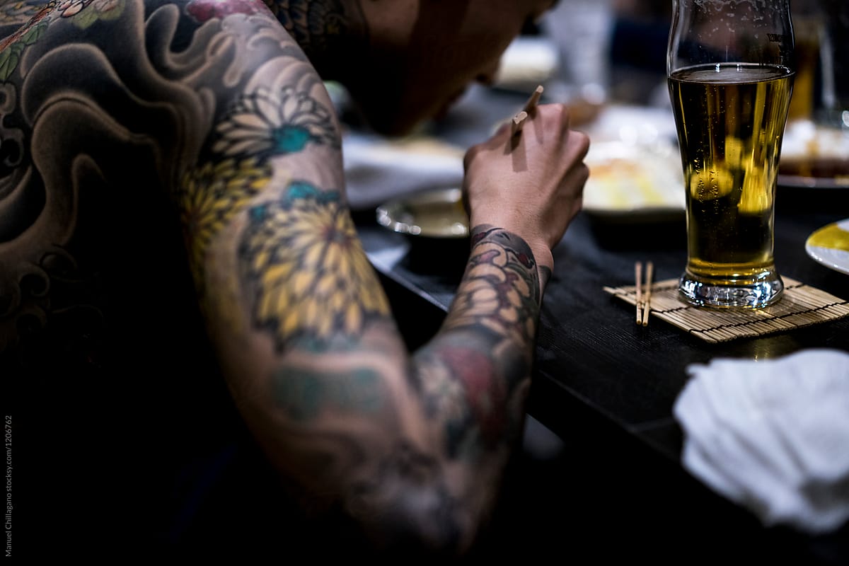 Tattooed Japanese Man eating with chopsticks