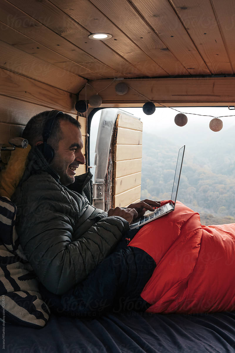 Man Chatting on laptop computer from his camper van