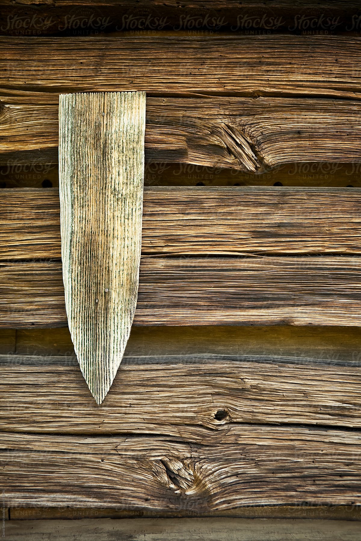 Weathered wooden arrow on a log building