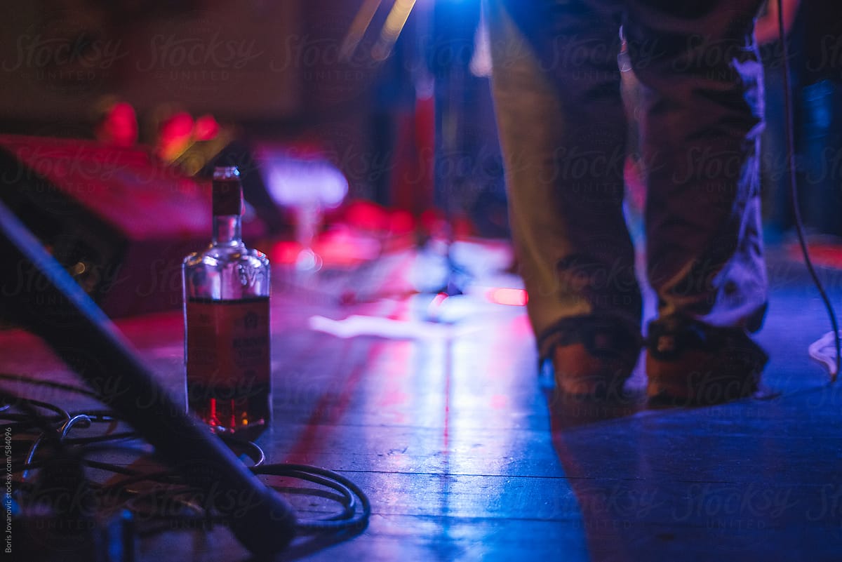 Bottle of alcoholic drink and man standing on stage