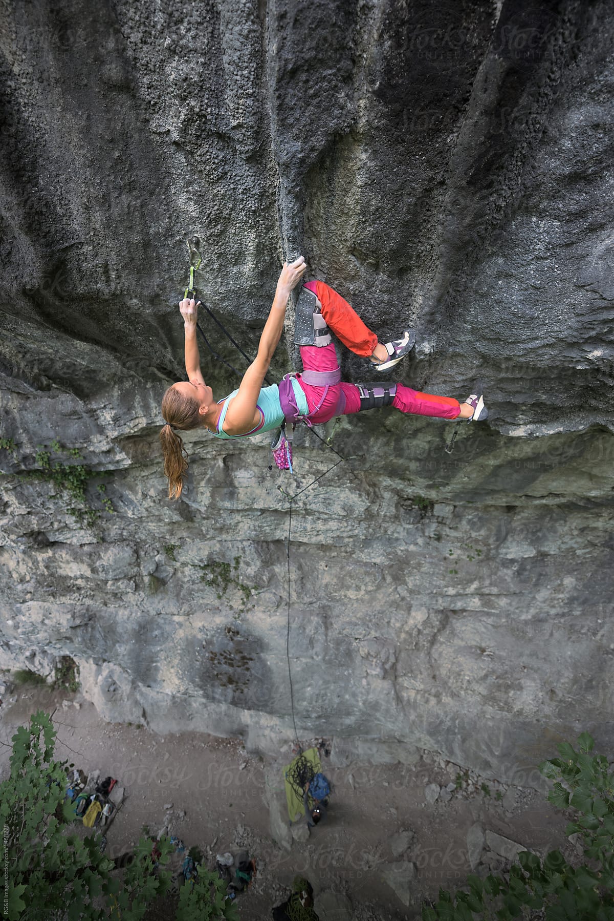Female rock climber clipping the safety rope on quickdraw