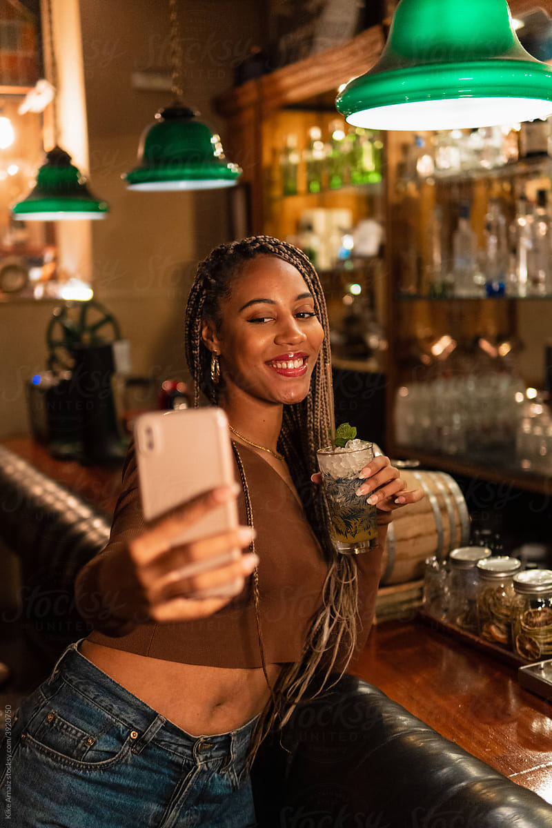 Trendy black female taking selfie in bar