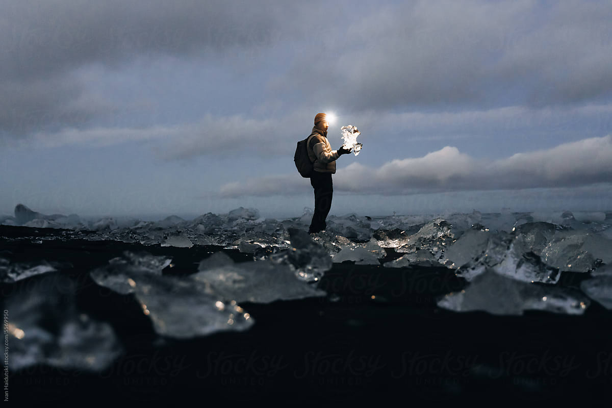 traveler holding a large ice floe block. Arctic wilderness concept.