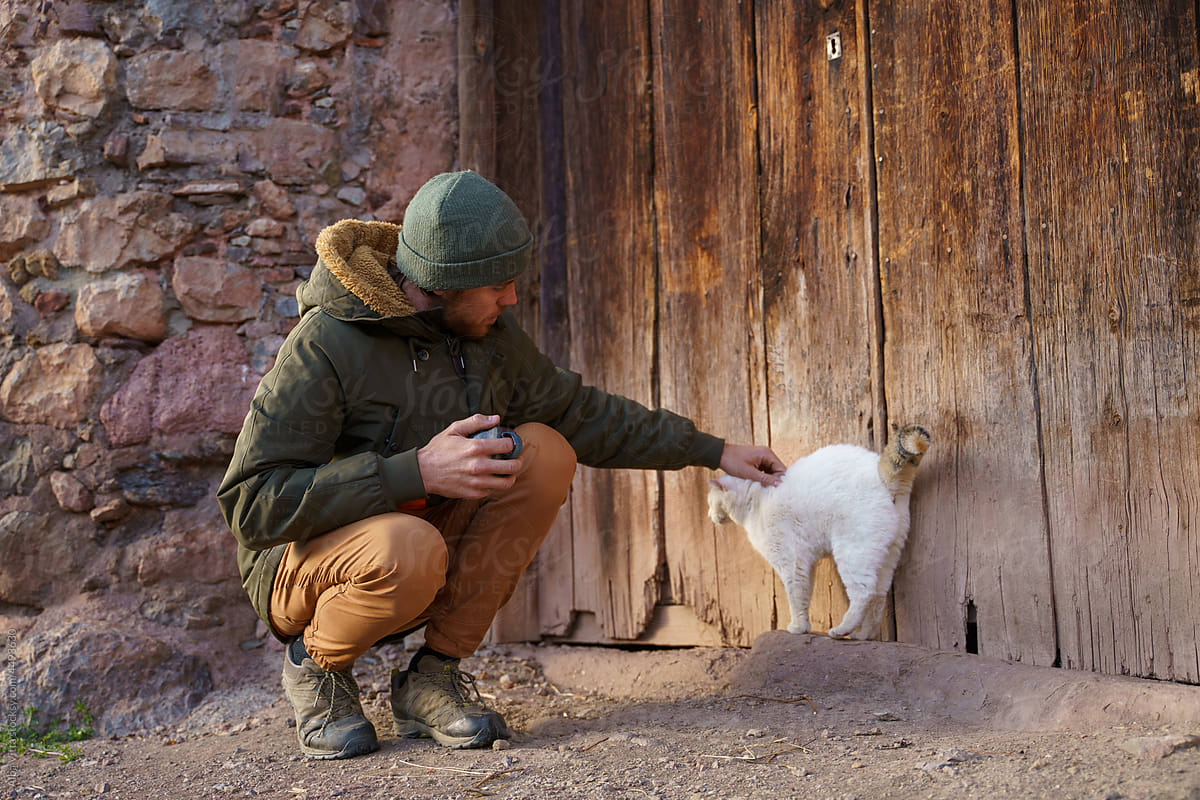 Man petting cat in rural village