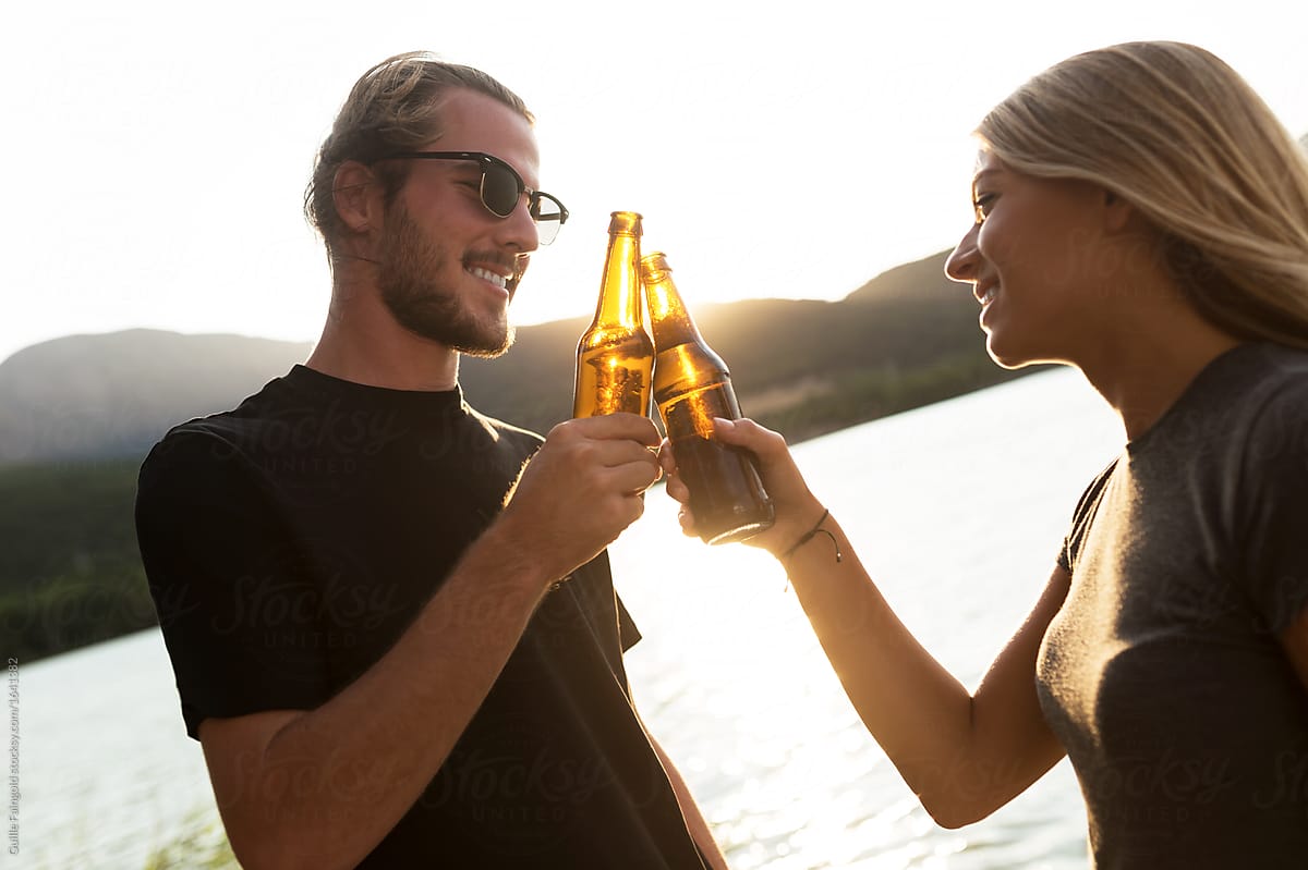 young couple toasting with beer on dock