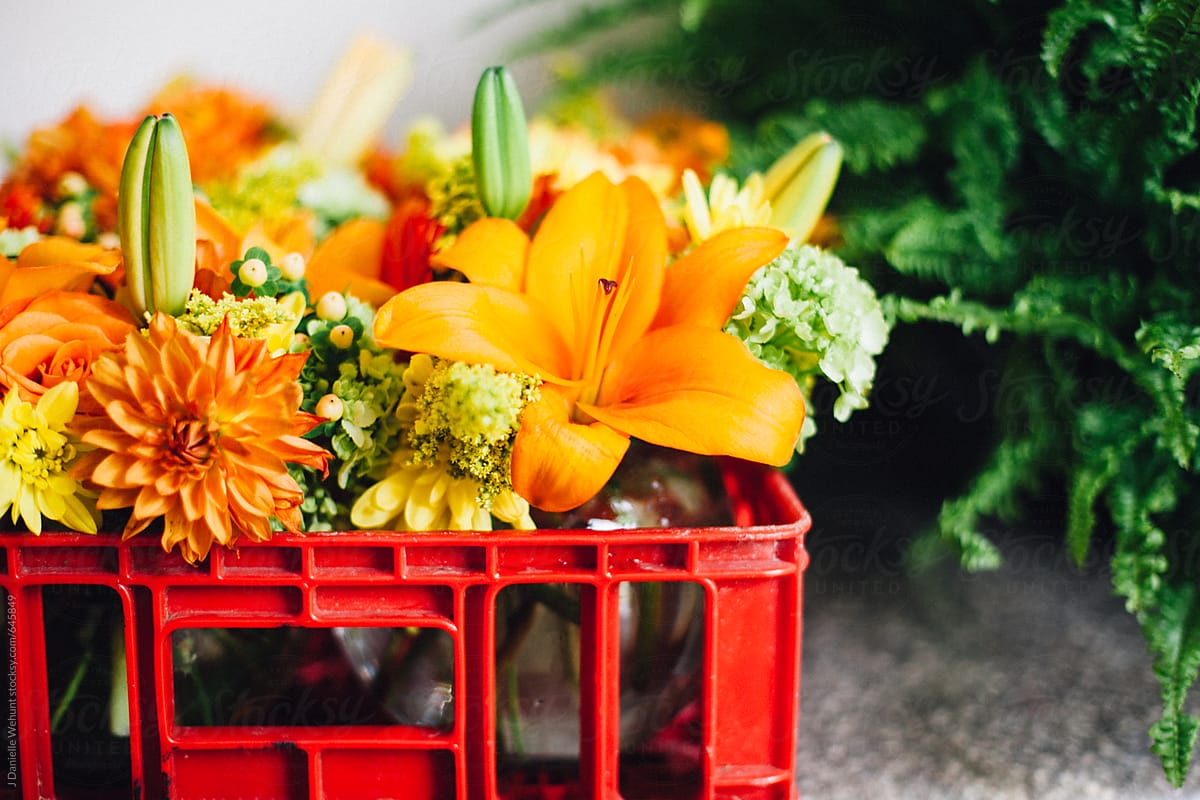 A bouquet of orange and yellow flowers in a red crate.