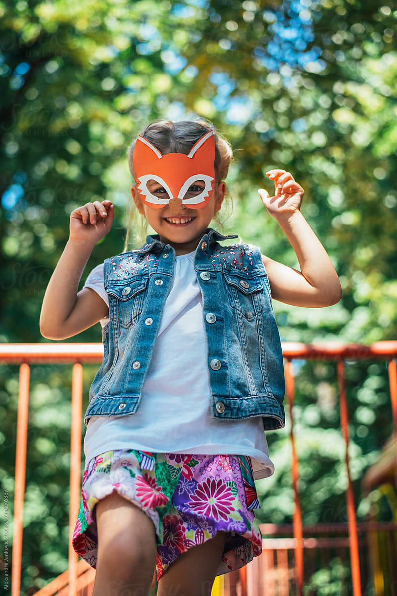 Cute little girl with fox mask playing outdoors