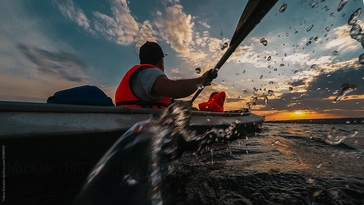 Father and a son go kayaking in the sunset
