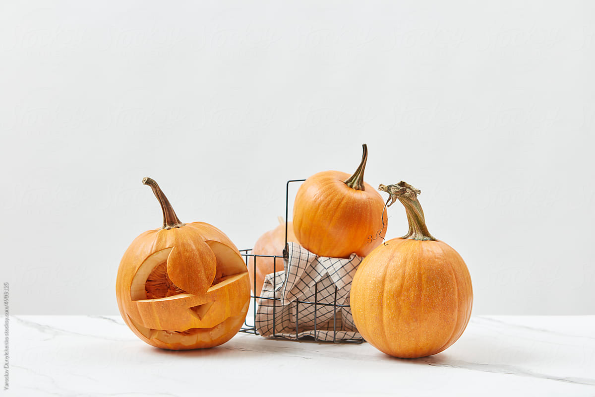 Pumpkin with Halloween carving in wire basket.