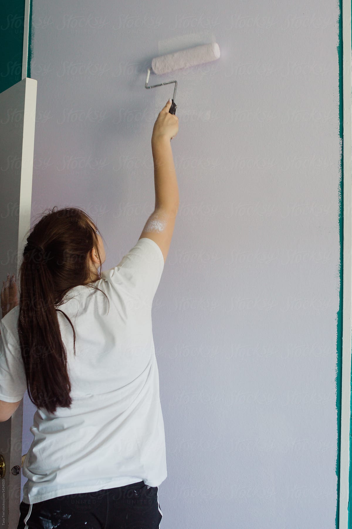 teenager rolls paint along bedroom wall