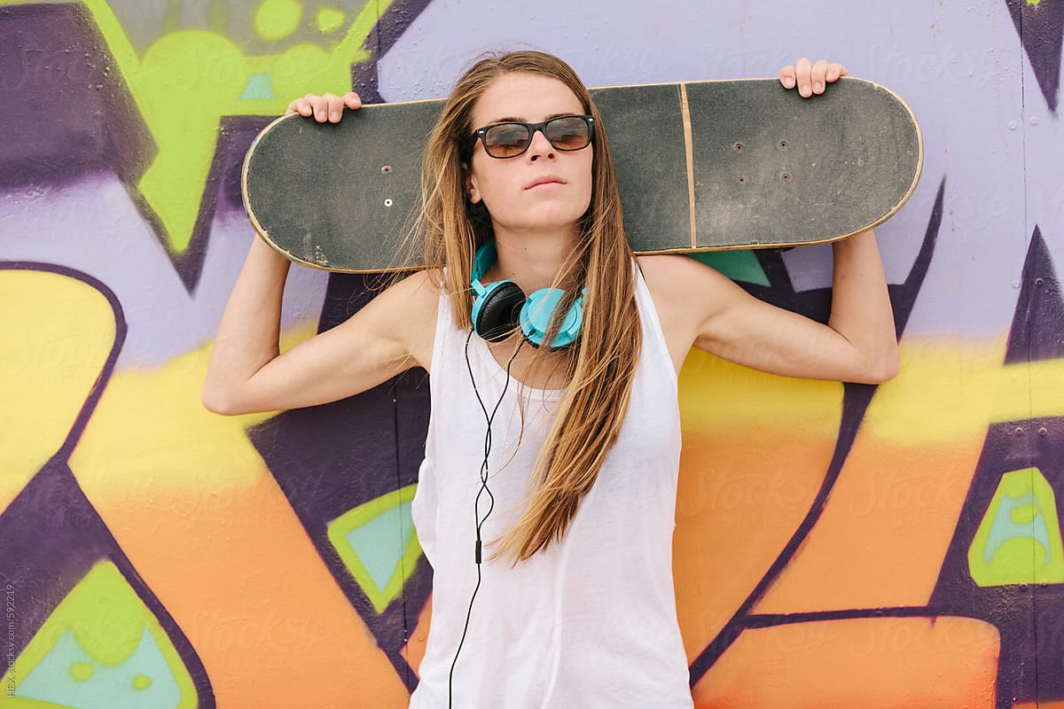 Pretty Woman With Skateboard in front Of a Colorful Painted Wall