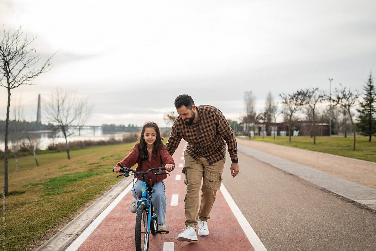 father teaching his daughter to ride a bicycle