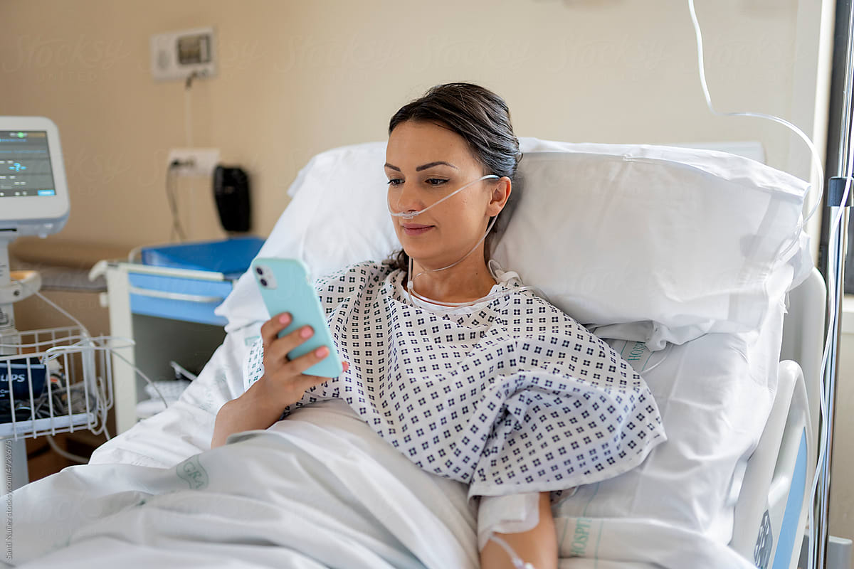 Patient woman using mobile in a hospital bed