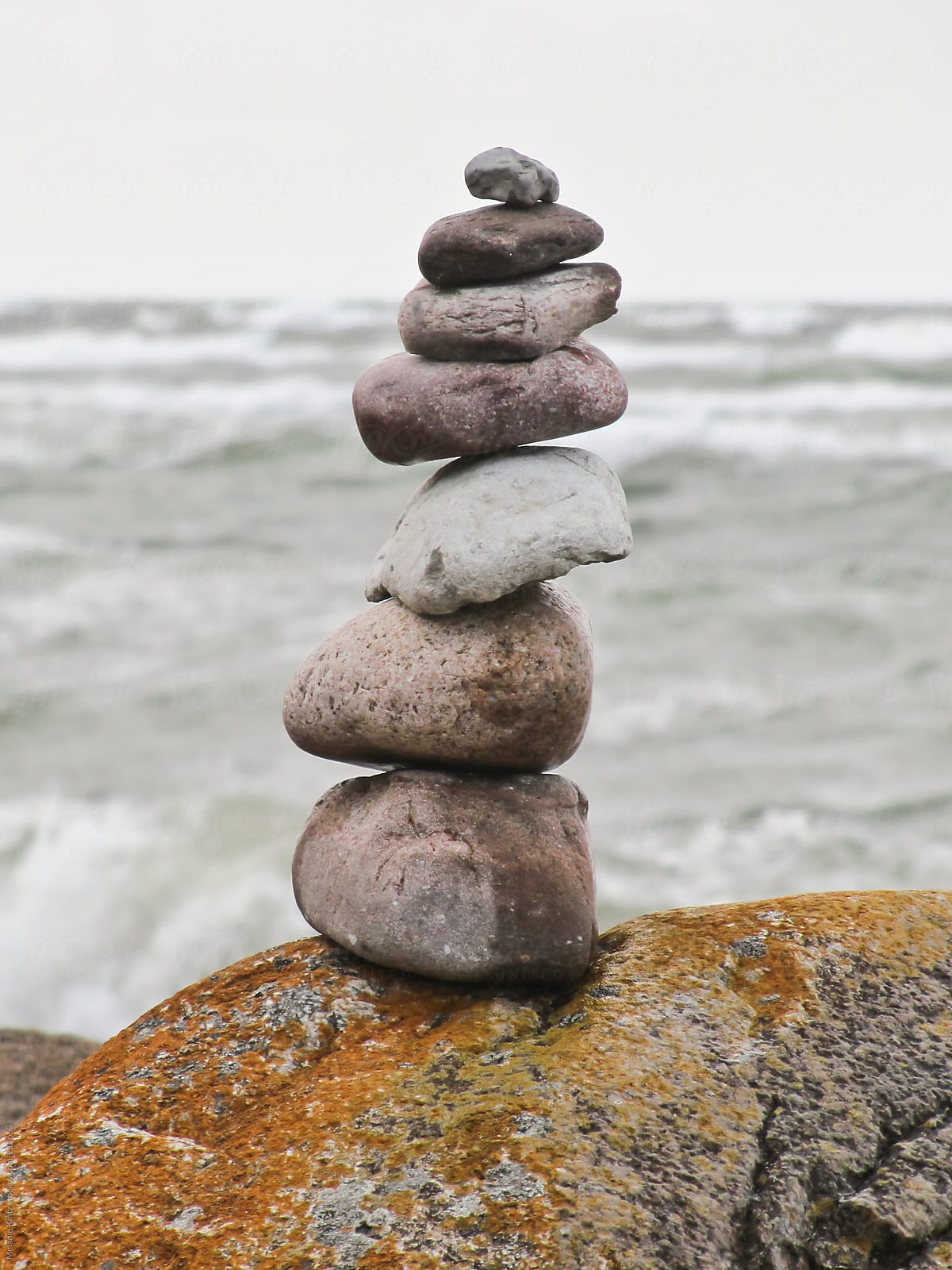 Pile of rocks balanced on a beach before stormy sea