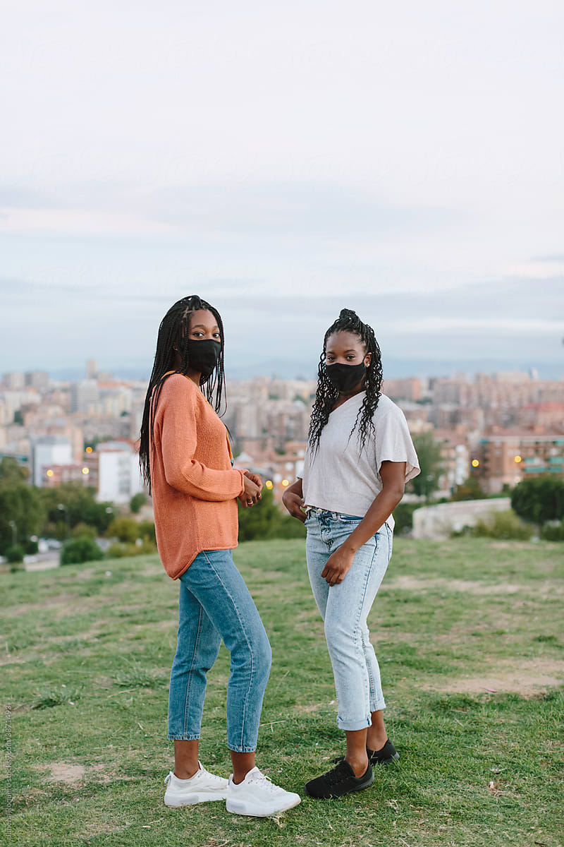 Black women with face mask outdoors looking at camera.