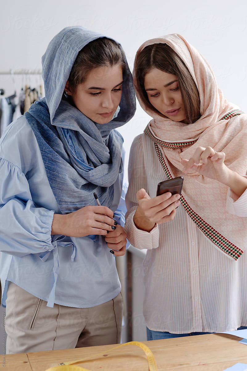Women collaborating clothes watching smartphone
