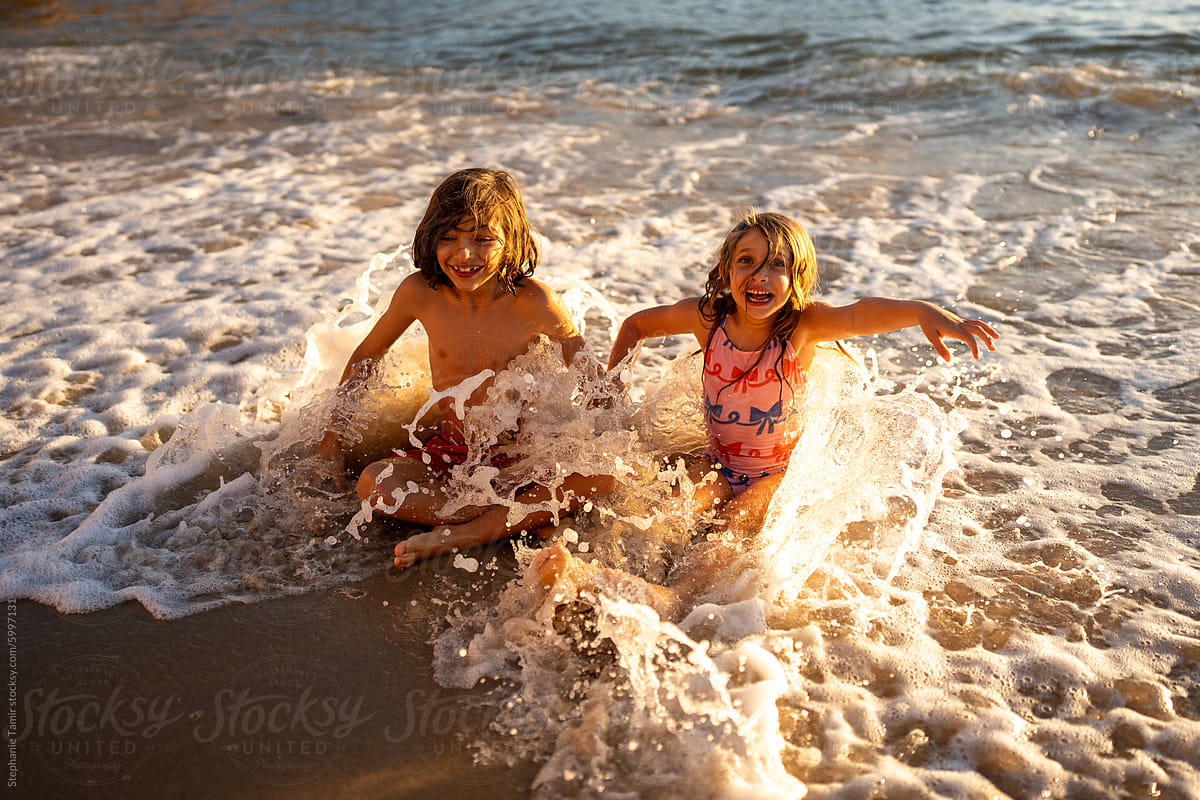 Kids playing in the water with the waves on an empty beach,