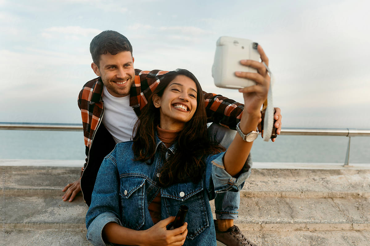 happy couple smiling and making selfie with polaroid camera
