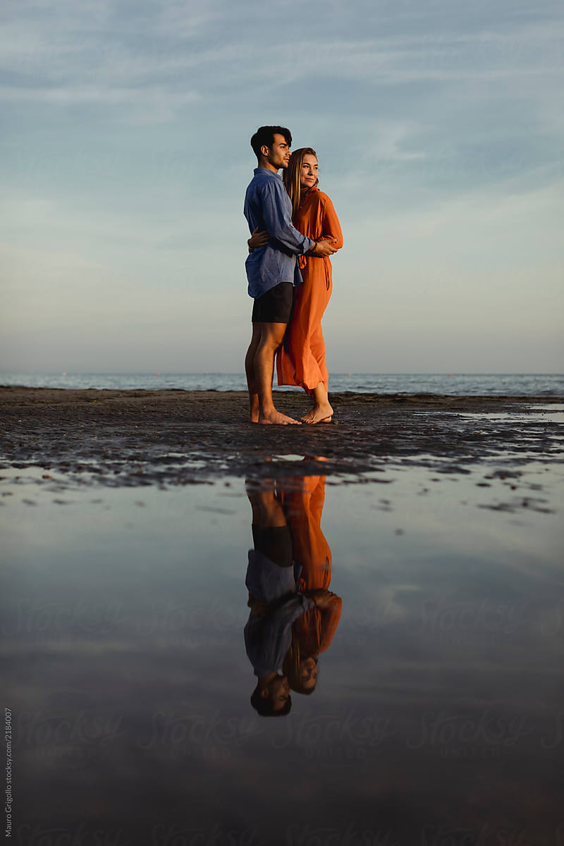 Elegant Couple walks on the beach at sunset. Romantic moments.