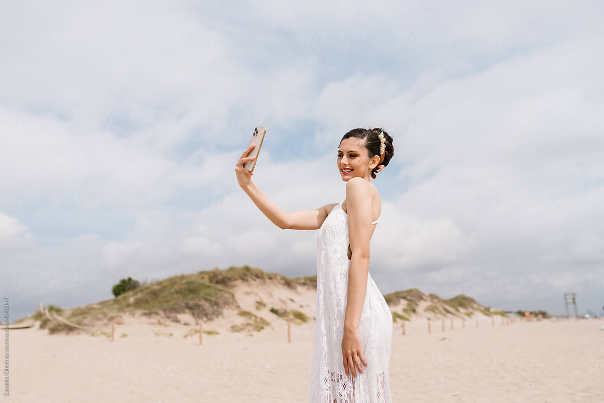 Bride taking selfie on beach
