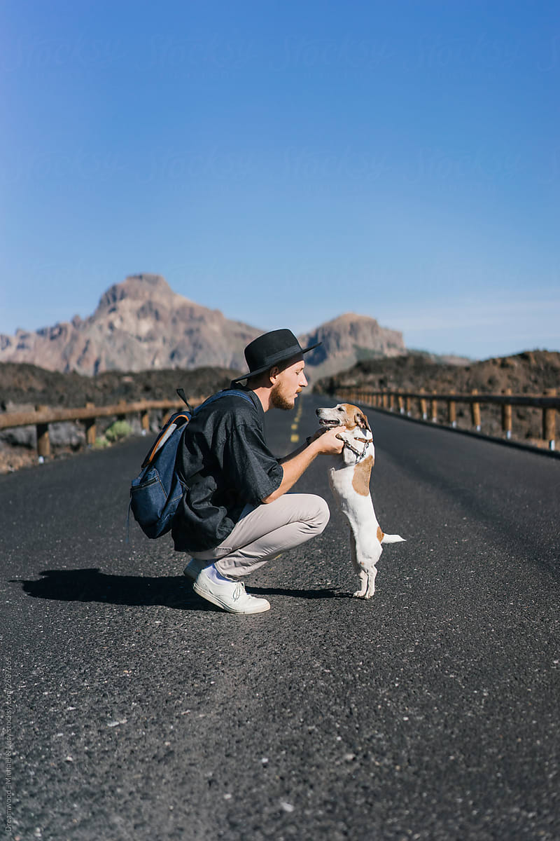 Adult man with dog on hands on road