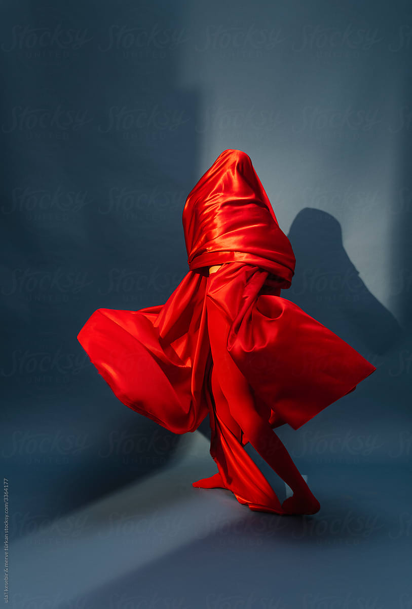 woman playing with red silk fabric on blu background
