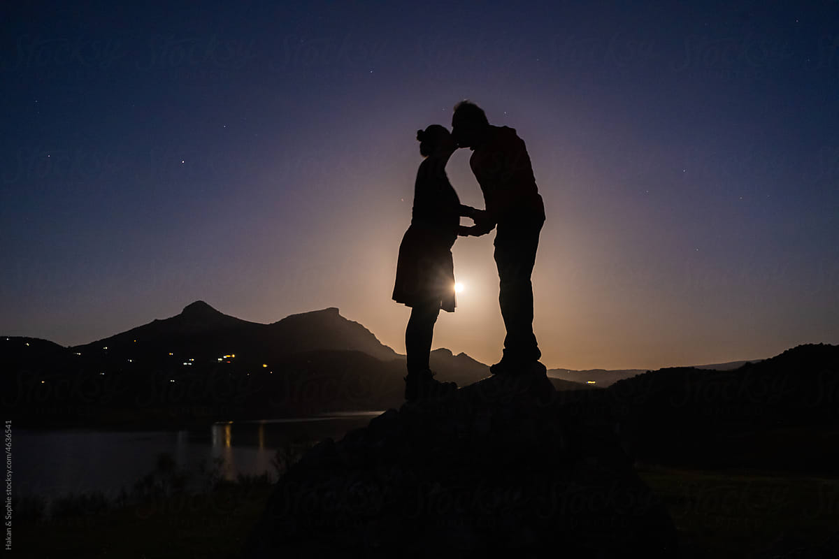 couple kiss as the full moon rises