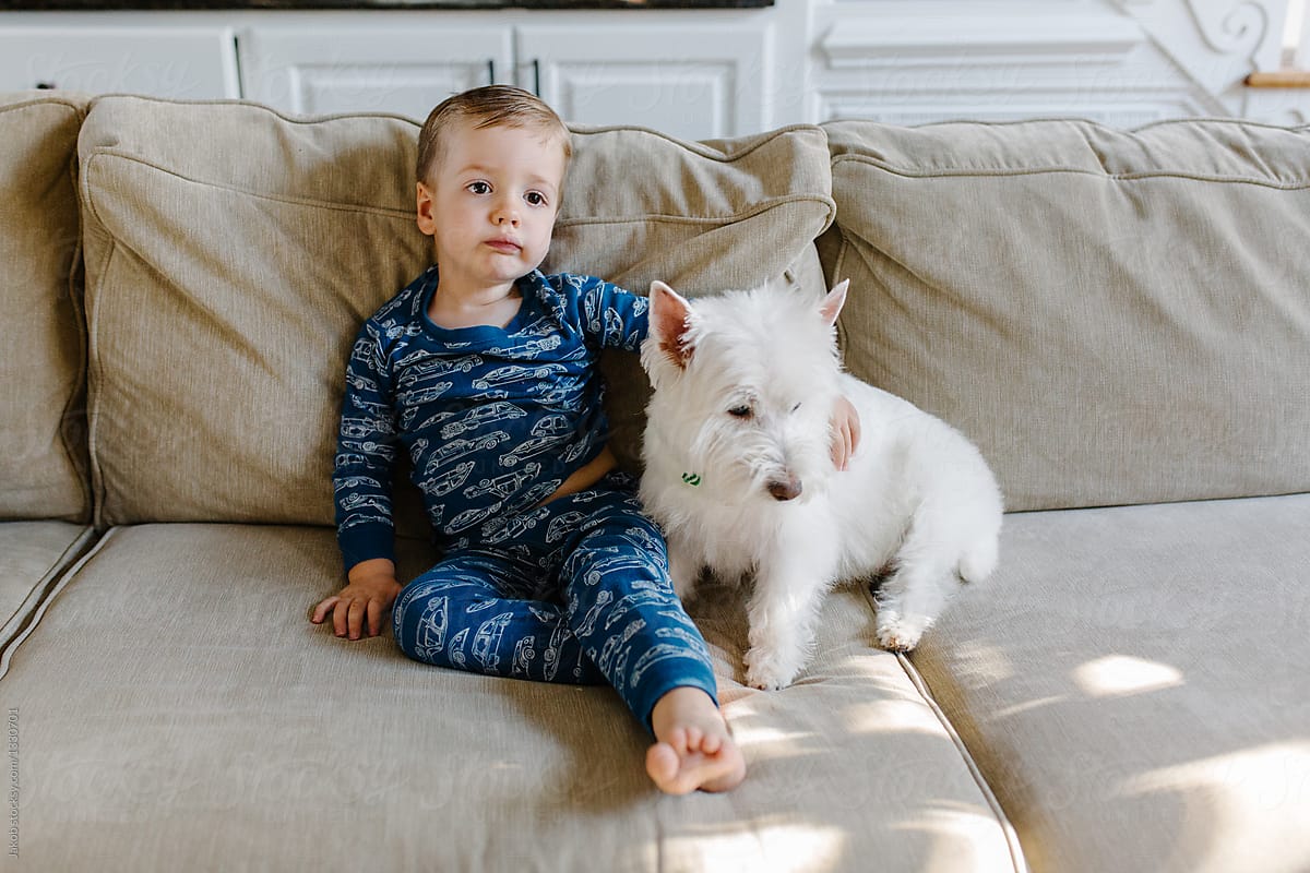 Cute young boy in a pajama looking bored next to his dog