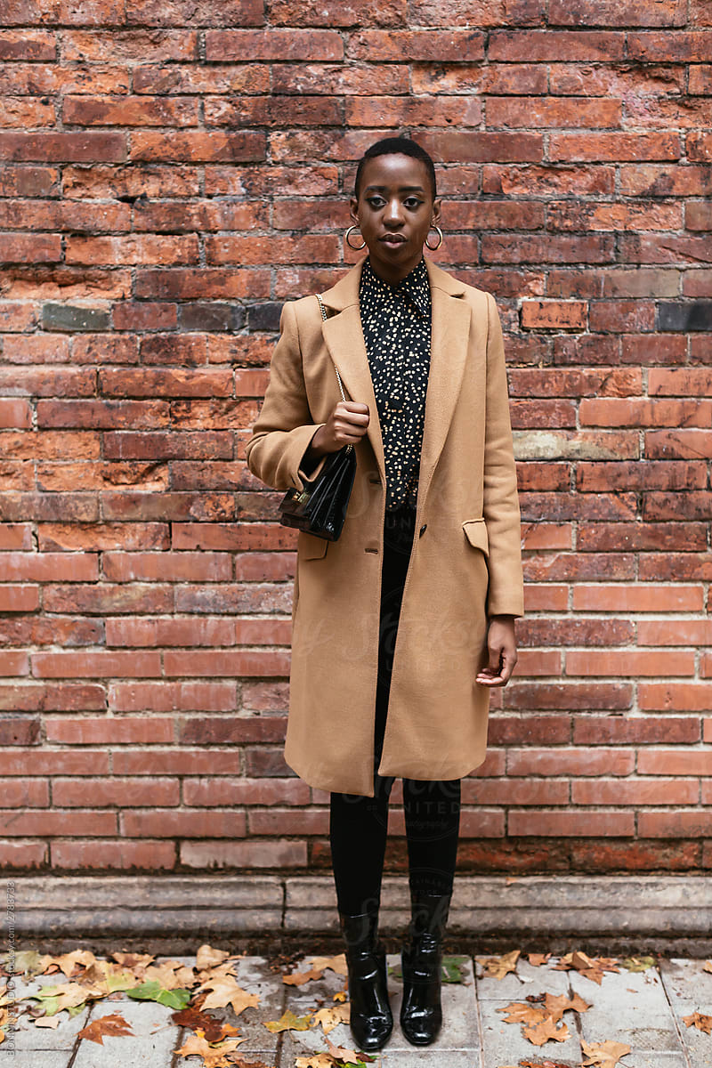 Stylish black woman against brick wall