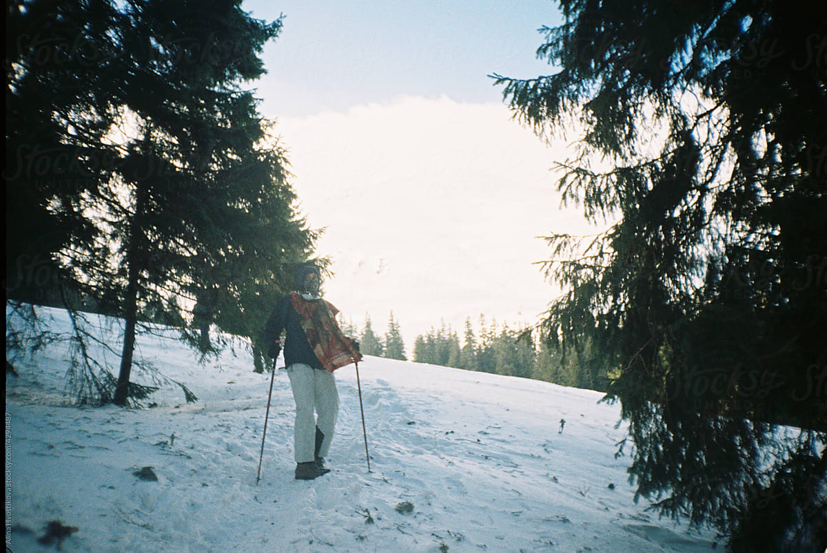 Traveler on snowy slope near trees