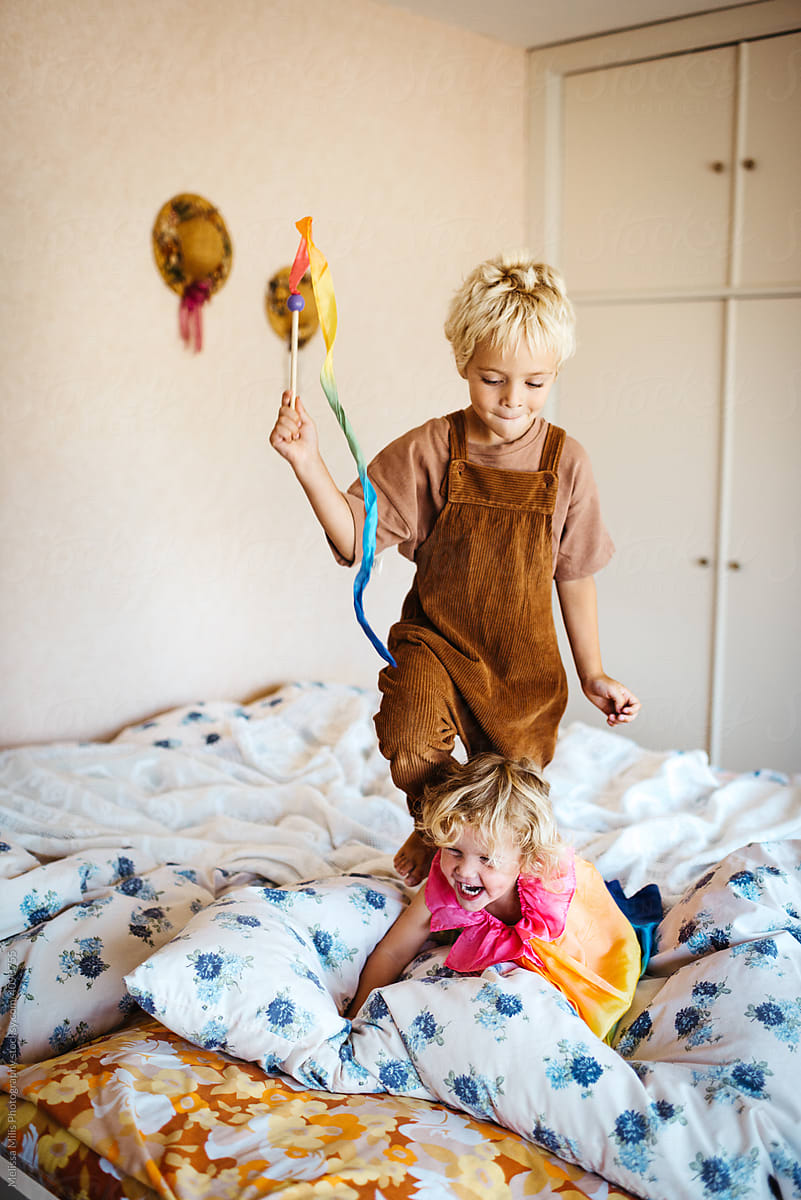 Two kids dressed up playing in the bedroom, having fun