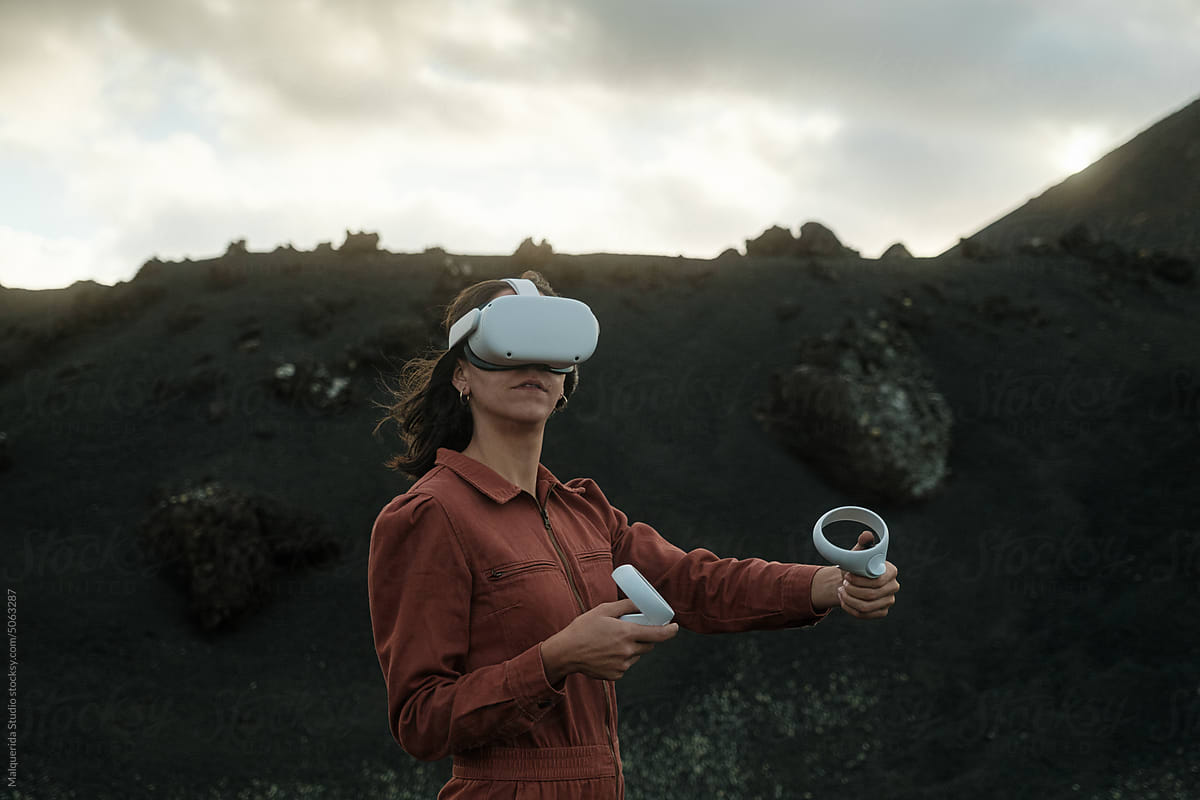 Woman using VR goggles and joysticks outdoors