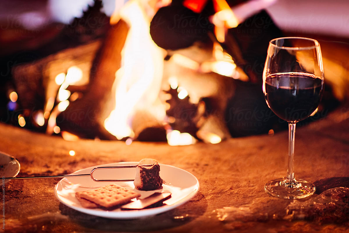 S\'mores and a glass of red wine beside a camp fire at night