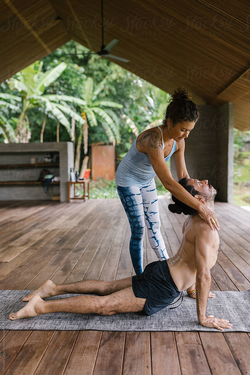 Female yoga instructor correcting her male student during a class