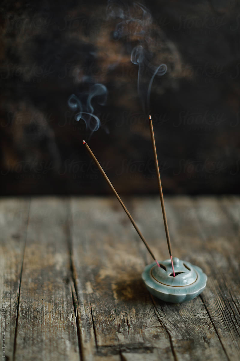 Two incense sticks burning standing in ancient china holder