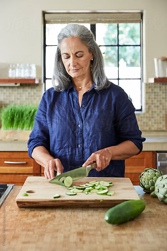 Mature woman preparing a healthy salad in the kitchen at home