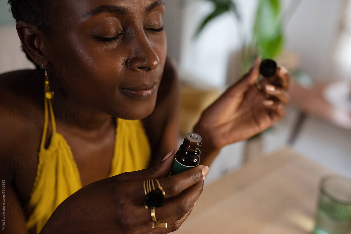 Black woman smelling aromatic oil at home