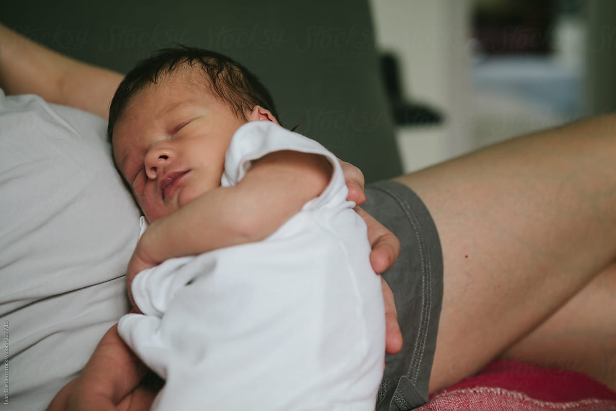 One week old baby boy sleeping on his mother\'s belly