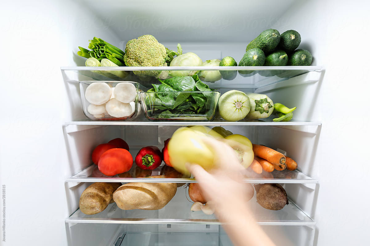 Hand in motion blur filling up the fridge with vegetables