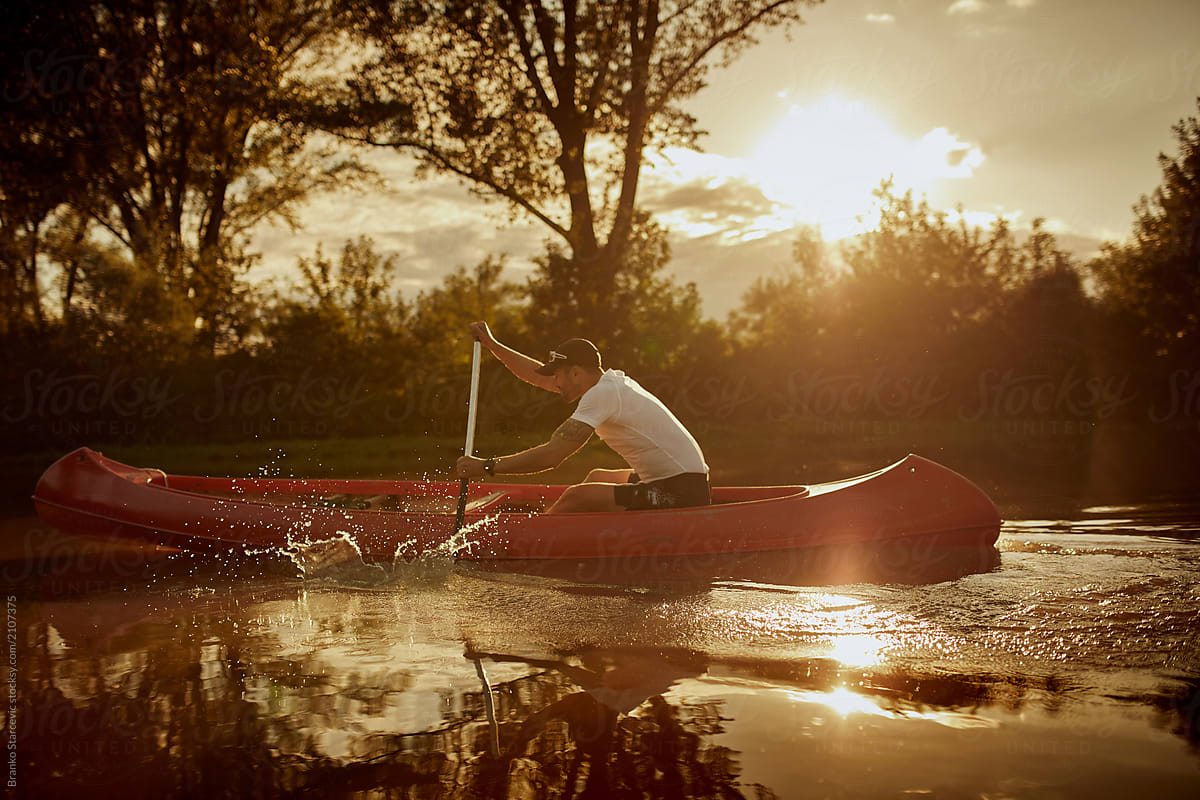Man paddling red canoe in the river.