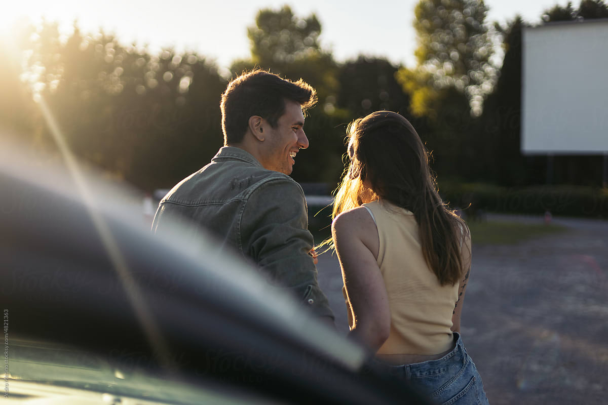 Couple leaning on car at sunset