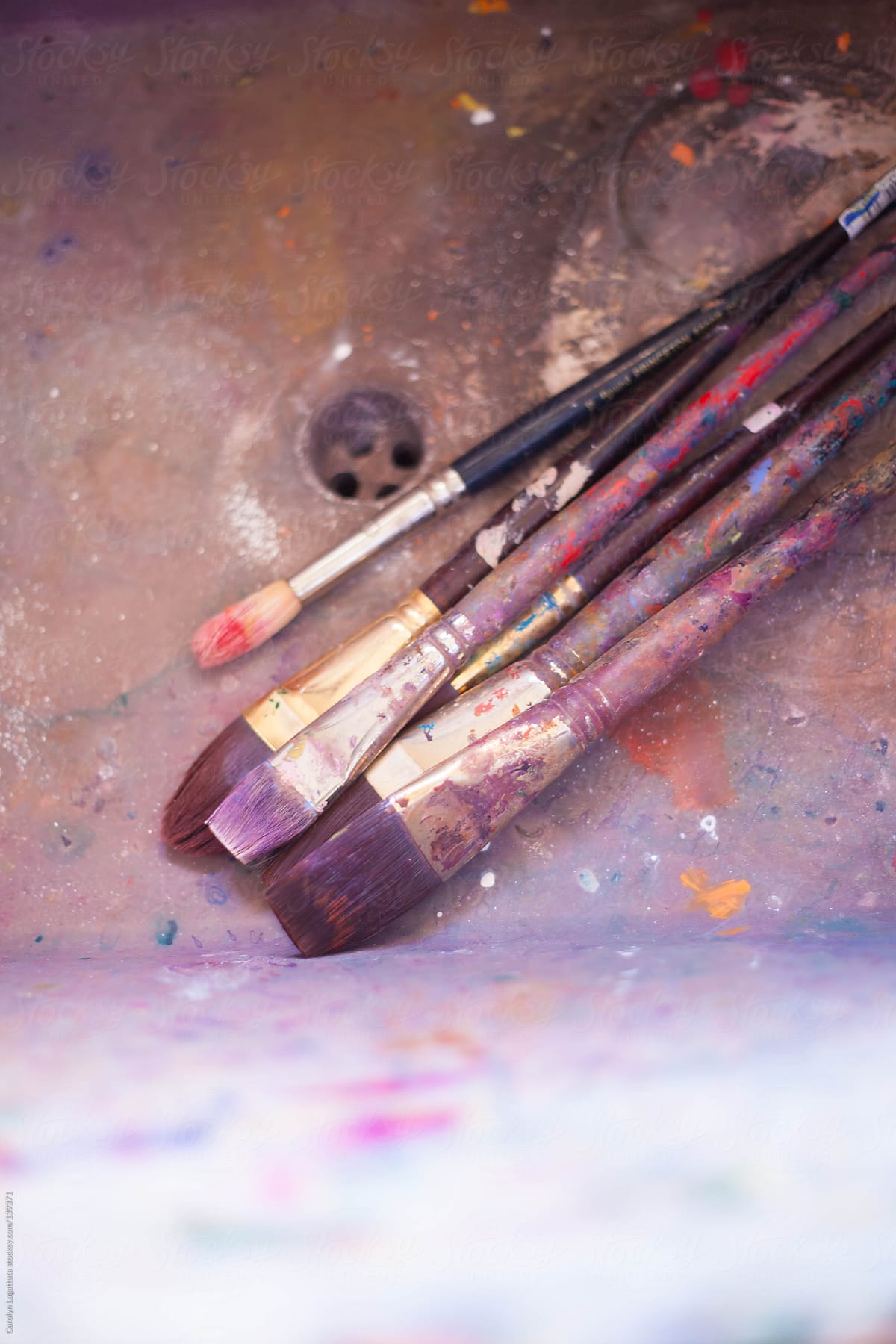 An artist\'s brushes in the sink - splattered with paint