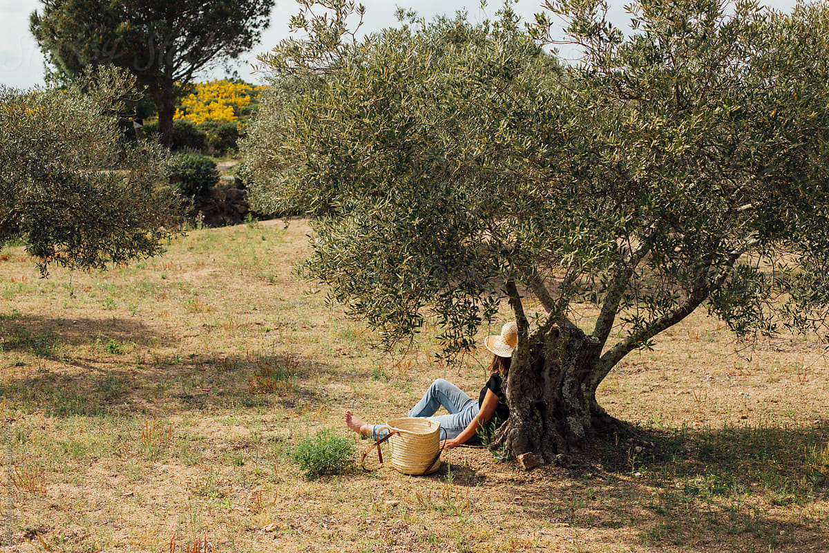 Young woman sitting on the ground under a tree taking a break