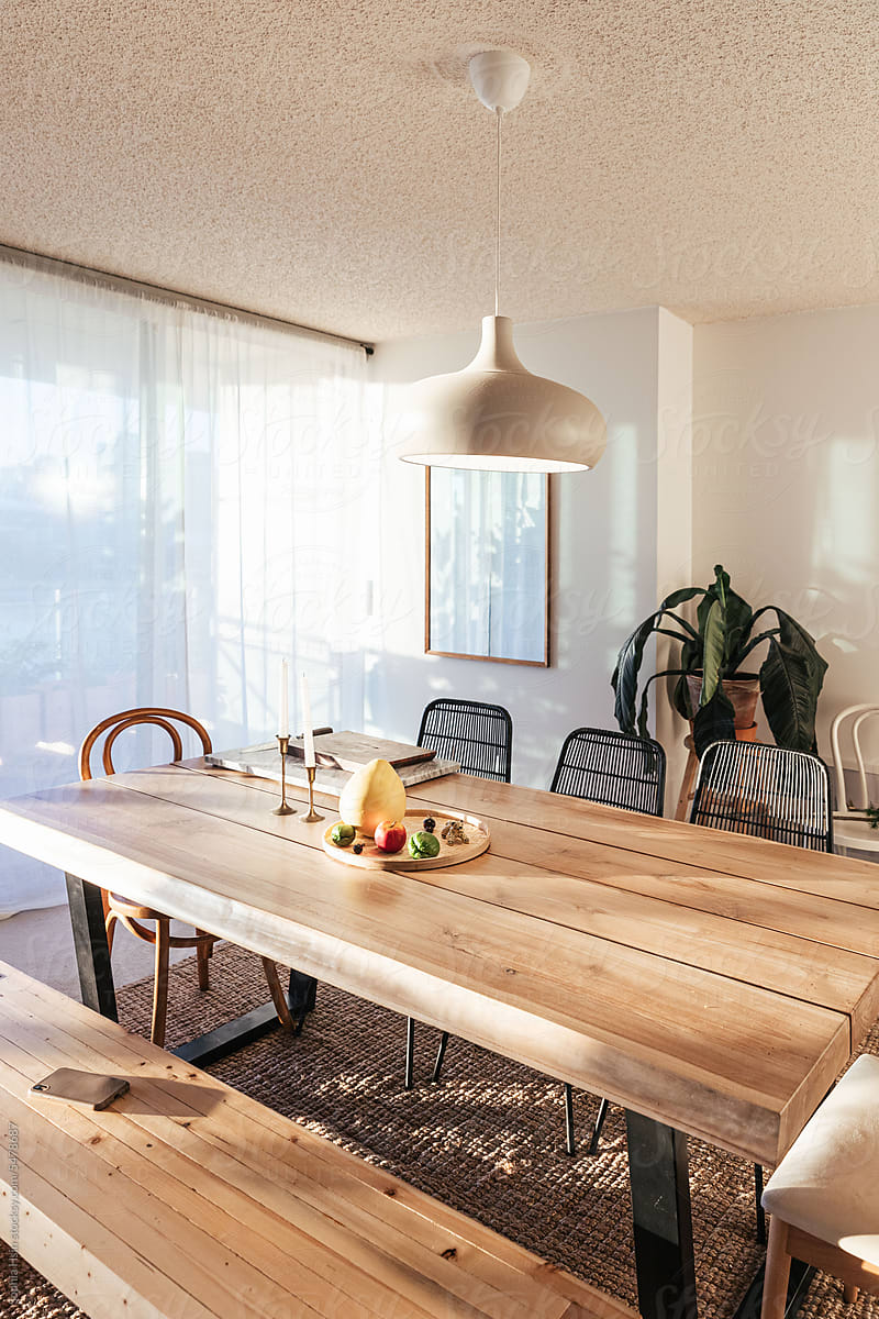 Bright dining room with wood table, plants, and hanging light pendant